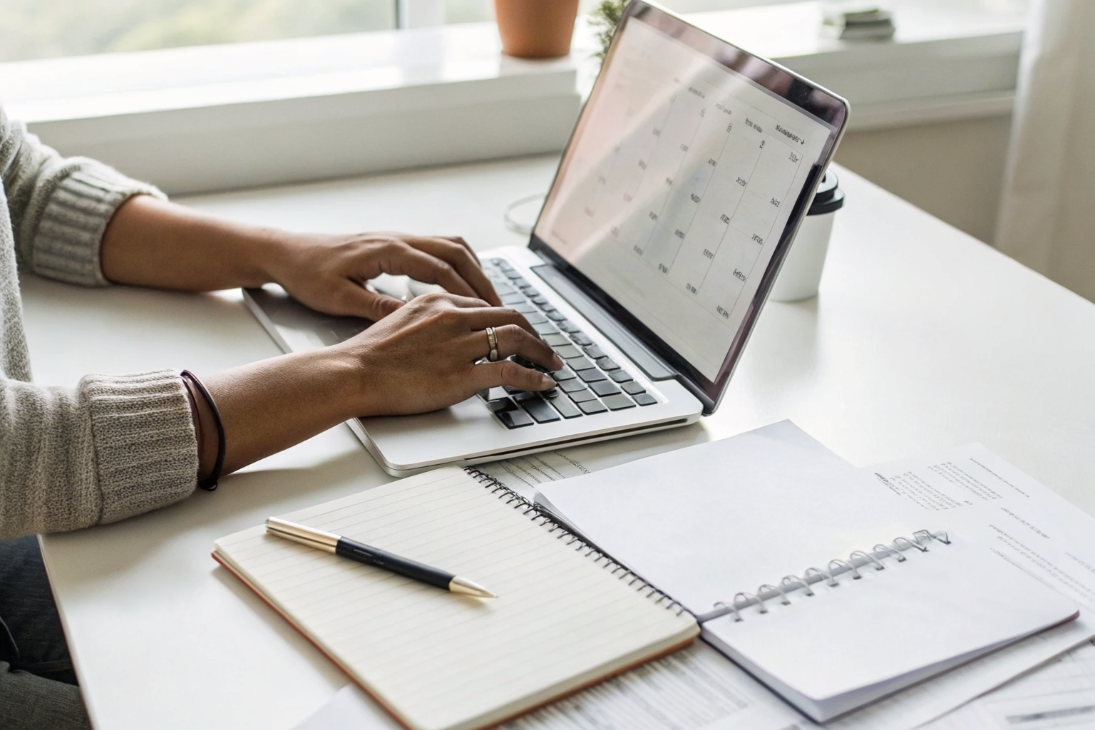 Person typing cancellation notice with calendar on desk.