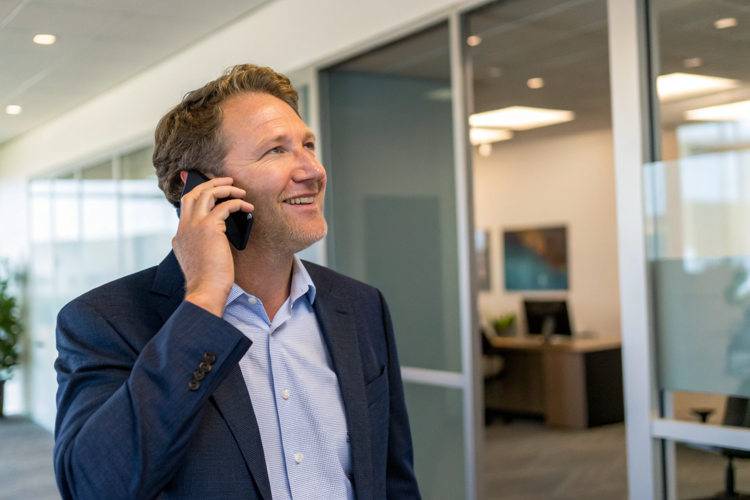 Business owner in Scottsdale listening to a phone call, satisfied expression.