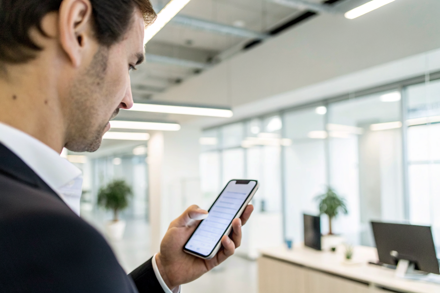 Business person with smartphone showing SMS triggers in office lighting